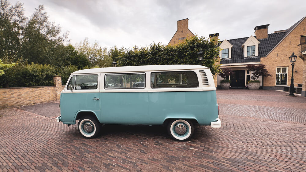 Zijaanzicht van de VW T2 op de oprit, met witte wielen.