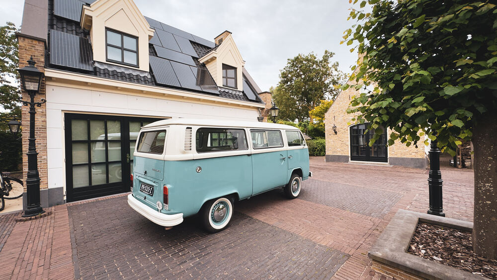 De zeegroene bus naast een boom voor de garage.