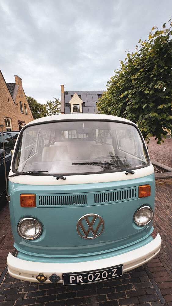 De VW-bus recht van voren, staand portret met de twee koplampen en het logo.